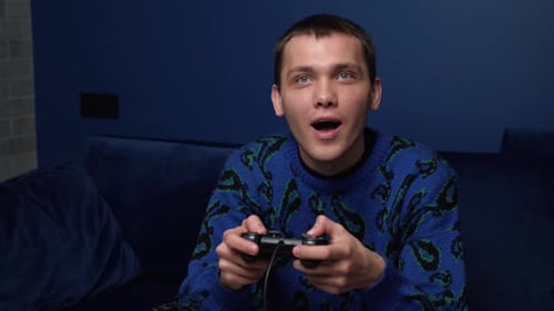 Front View of an Excited Caucasian Man Playing Video Games and Using Joystick Controller. Happy Man