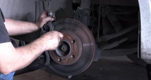 Man Repairing Car Brake Rotor in Garage