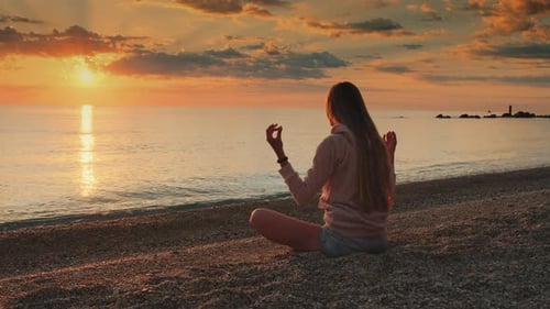 Femme méditant sur la mer avant le coucher du soleil