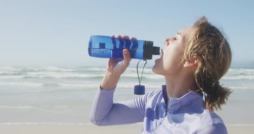 Athletic woman drinking water on the beach