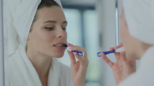 Young Woman Brushing Teeth in Bright Bathroom