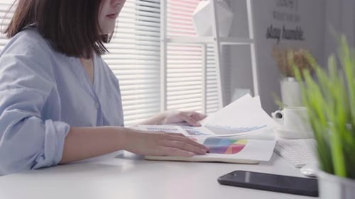 Young Woman Typing at Desk with Computer and Charts