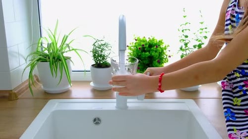 Girl Fills Glass with Water at Kitchen Sink
