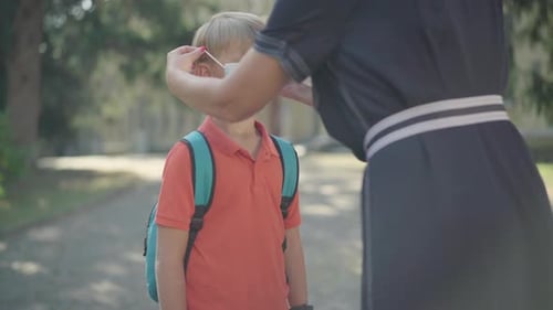 Unrecognizable Mother Putting Face Mask on Cute Schoolboy. Caucasian Boy Gesturing Yes By Shaking