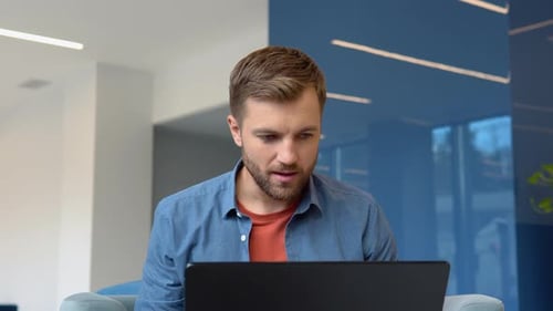 Man Celebrating Success Using Laptop in Modern Office