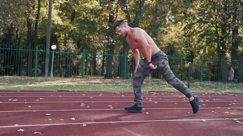Muscular Man Stretching on Outdoor Running Track
