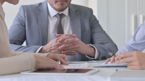 Close up of Hands of Businessman with Female Colleagues Discussing Documents