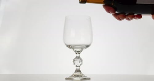 Nahaufnahme. Der Rotwein fließt in ein Glas, weißer Hintergrund