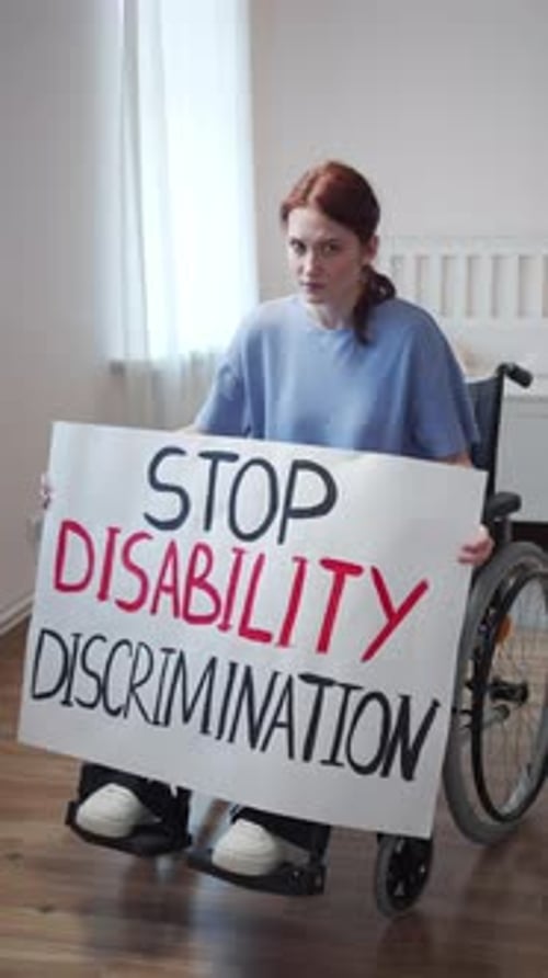 Woman in Wheelchair Holding 'Stop Disability Discrimination' Sign