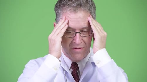Doctor Rubbing Temples in Discomfort and Stress
