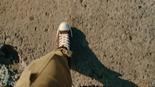 Closeup Top View of the Legs of a Man Walking on a Concrete Road