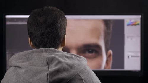 Young Adult Edits Portrait on Computer Monitor