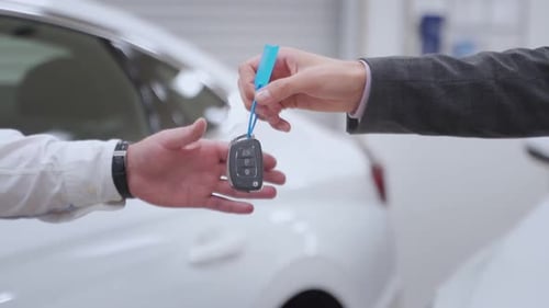 Car Dealer Handing Over New Car Key To Customer at Showroom