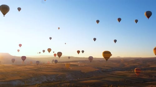 Hot Air Balloons Floating Over Desert Landscape at Sunrise