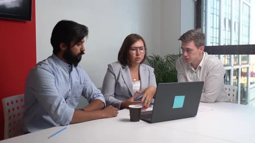 Three Colleagues Meeting Around a Laptop in Office