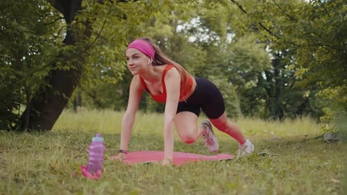 Athletic Sporty Fit Girl Doing Workout in Park on Sport Mat Performing Training Yoga Plank Pose