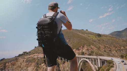 Adventurous Man Overlooking Scenic Mountain Bridge