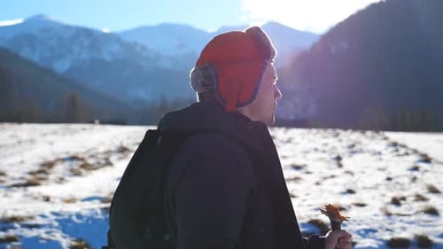 Side View of Young Hiker Going Nordic Walking with Sticks on Snowy Trail in Field at Mountain