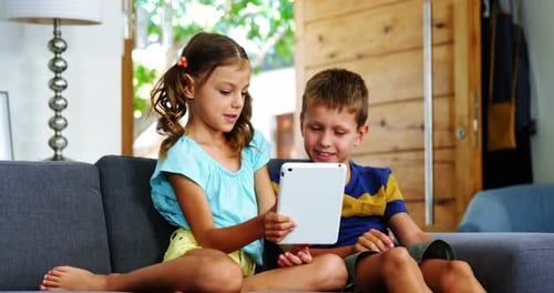Children Using Tablet on Sofa Together Indoors