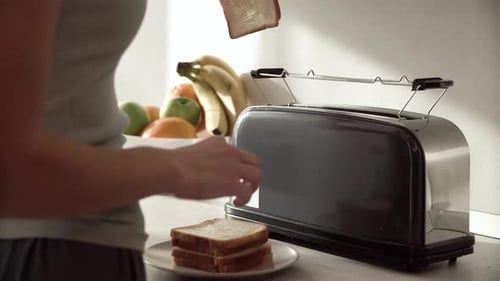 Woman making toast in bright kitchen