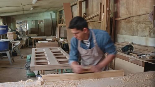 Young Adult Crafts Wood in Rustic Workshop
