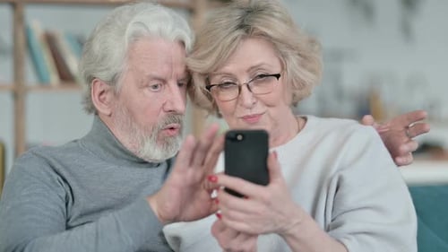 Senior Couple Looking at Phone Together in Home