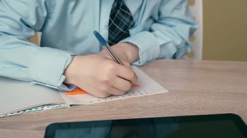 Boy Doing Math Homework at Table Indoors