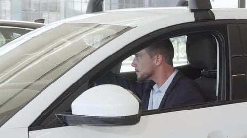 Young Adult Man Sits in New White Car