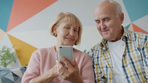Senior Couple Using Smartphone Together at Home