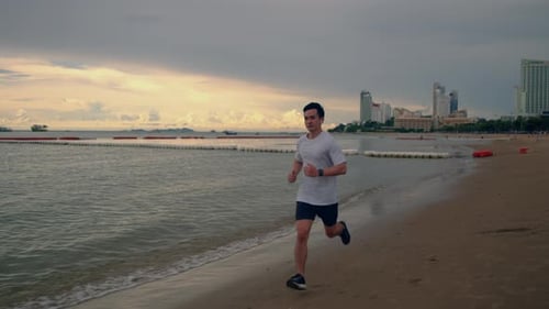 Young Asian sportsman running on the beach beautiful sunset.