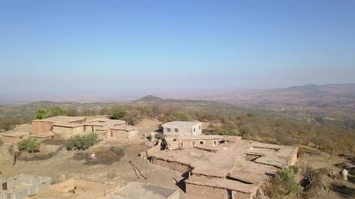 Drone view of the small town located on the rocky cliff; camera zoom out on the valley.