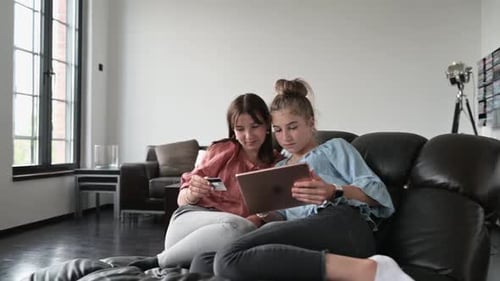 Two teenage girls using digital tablet to shop online