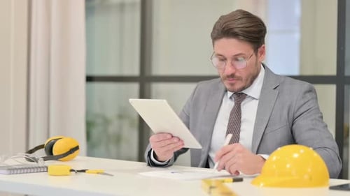 Techniker mittleren Alters schreiben Bericht bei der Verwendung von Tablet im Büro