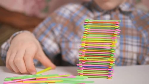 Niño construye una pirámide de palos de colores