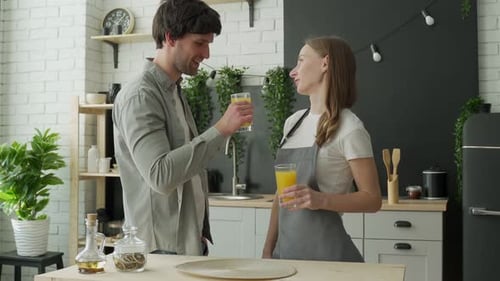 Couple Toasting Orange Juice in Kitchen