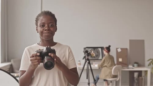 Smiling Woman Holding Camera in Studio Setting