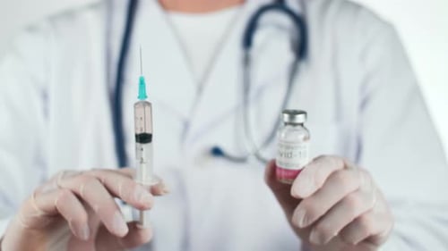 Medical Professional Holds COVID-19 Vaccine and Syringe