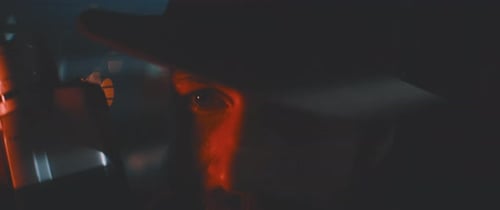 Close up of man through shutters and red lights using vintage camera