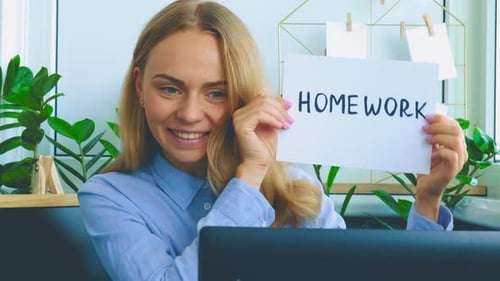 Woman Holds Homework Sign While Using Computer At Home