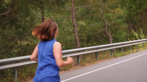 Woman running in morning mountain forest.