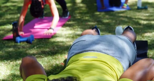 Group of people performing push ups in the park 4k