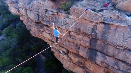 Male highliner walkng on a rope over rocky mountains 4k