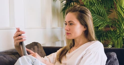 Woman Using Tablet on Couch in Home