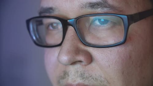 Hacker benutzt Computer bei Nacht, Bildschirmreflexion. Versteckter Mann benutzt Computer in der Nacht.