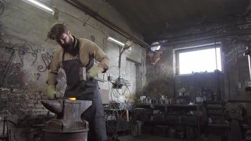 Bearded Blacksmith Forging Hot Metal with Hammer