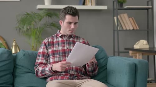 Man Reading Good News Excited Indoors on Couch