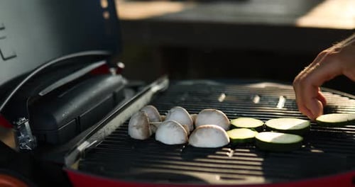 Close up on man's hand roasting vegetables on the barbecue gas grill