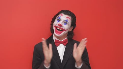 Der Clown beginnt die Aufführung in einem schwarzen Anzug mit buntem Make-up auf seinem Gesicht, isoliert auf einem roten