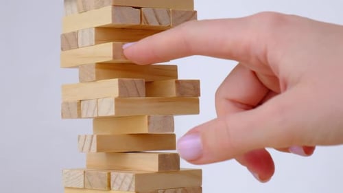 Female Hand Playing Wooden Block Removal Tower Game at Home