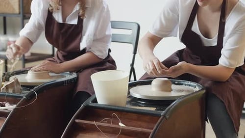 Two Female Ceramic Artists in Apron Using Clay Material Working in Potter Studio. Evening Freelance